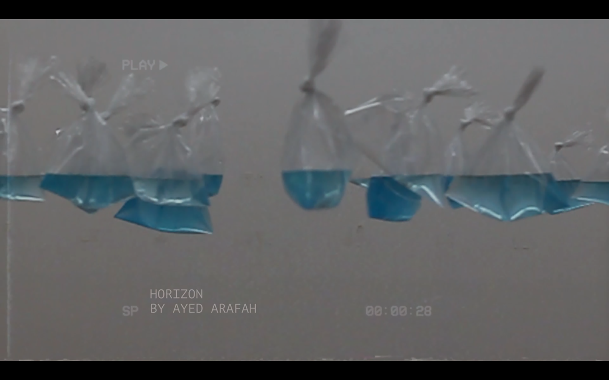 bags of blue water hang in front of a white wall so that they form a horizon line.